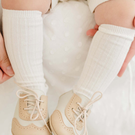 Photo of a baby wearing the Cream Ribbed Socks made from a soft cotton blend and featuring a ribbed pattern