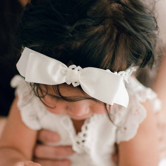 Baby wearing a Lily bow headband made of soft, cotton lace and featuring a silk ribbon bow
