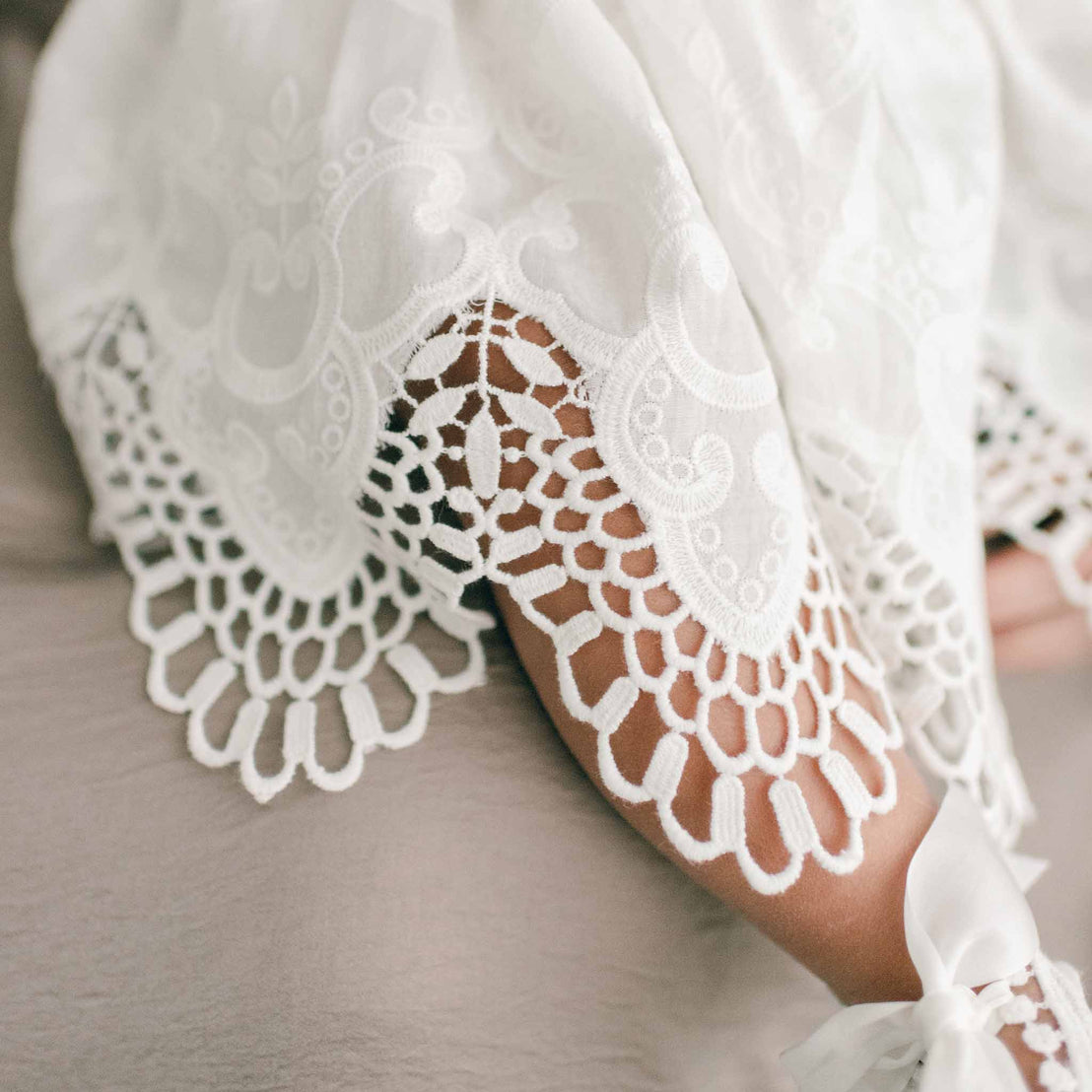 Detail of bottom skirt of a christening romper dress worn by a baby girl