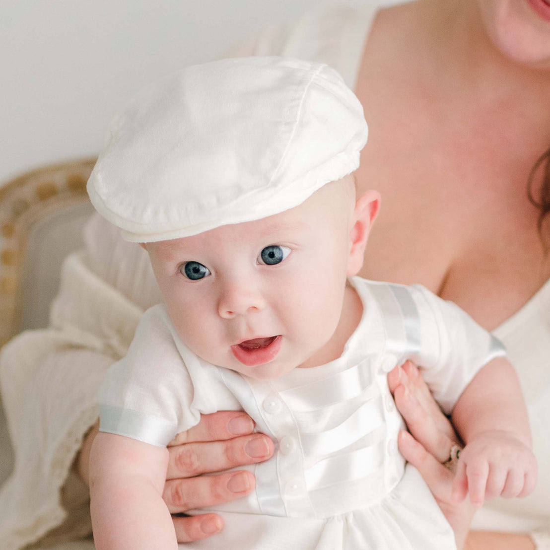 Baby boy sitting on his mother's lap and wearing the Owen Linen Newsboy Cap.