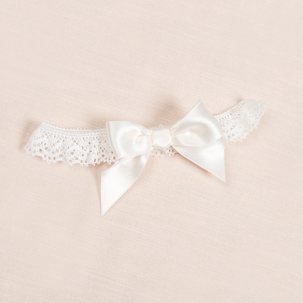 Flat lay photo of Penelope lace headband with bow.