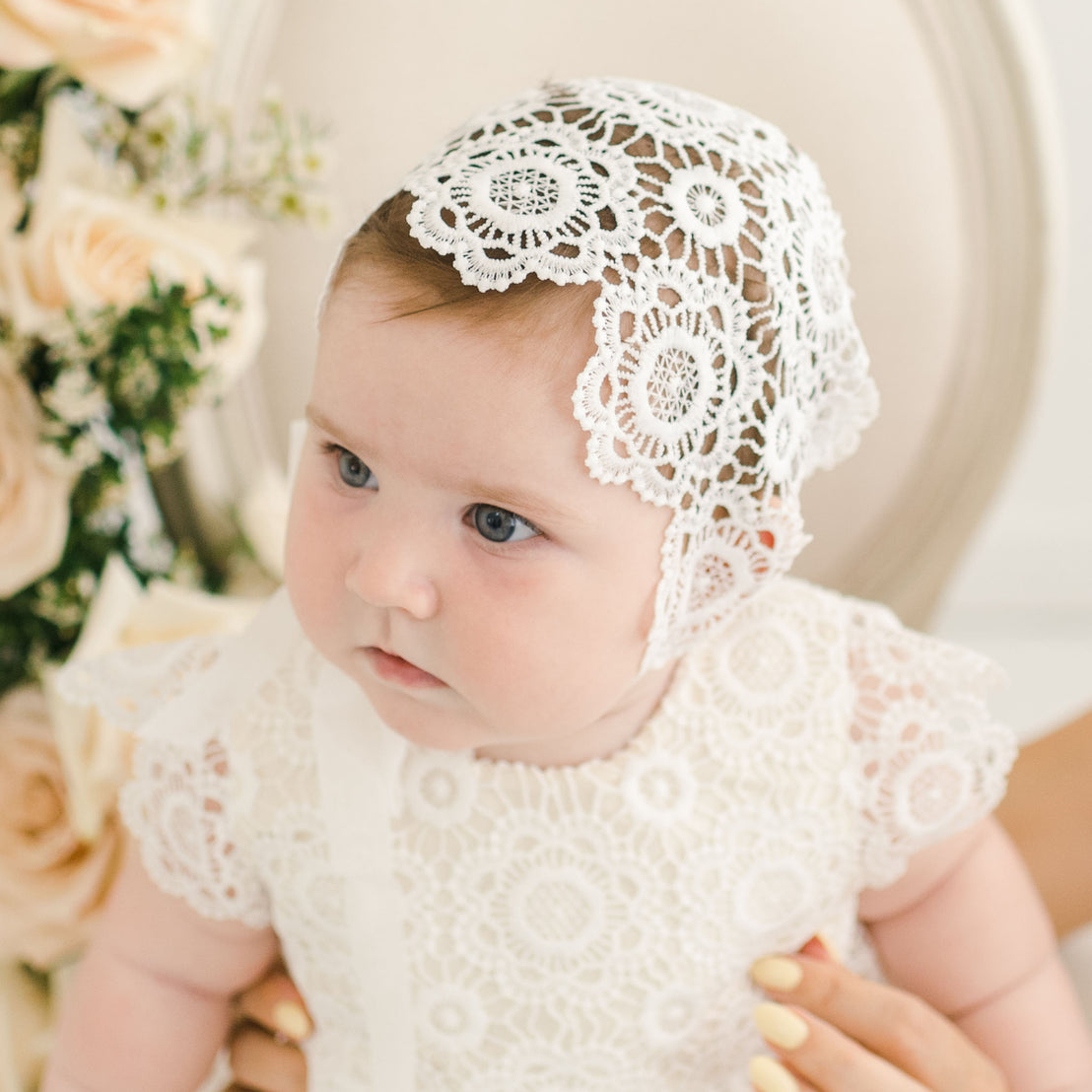 Baby girl wearing lace christening bonnet.