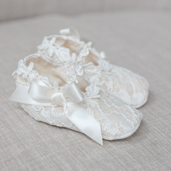 Lace baby shoes with a bow on a light gray background