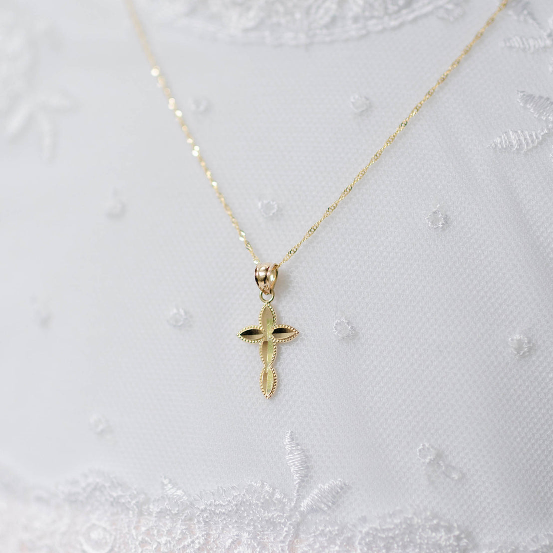 Gold cross pendant necklace on a white textured background