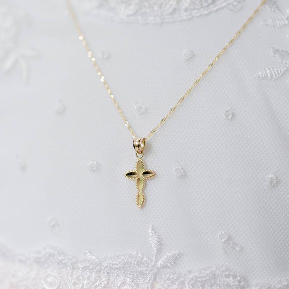 Gold cross pendant necklace on a white textured background