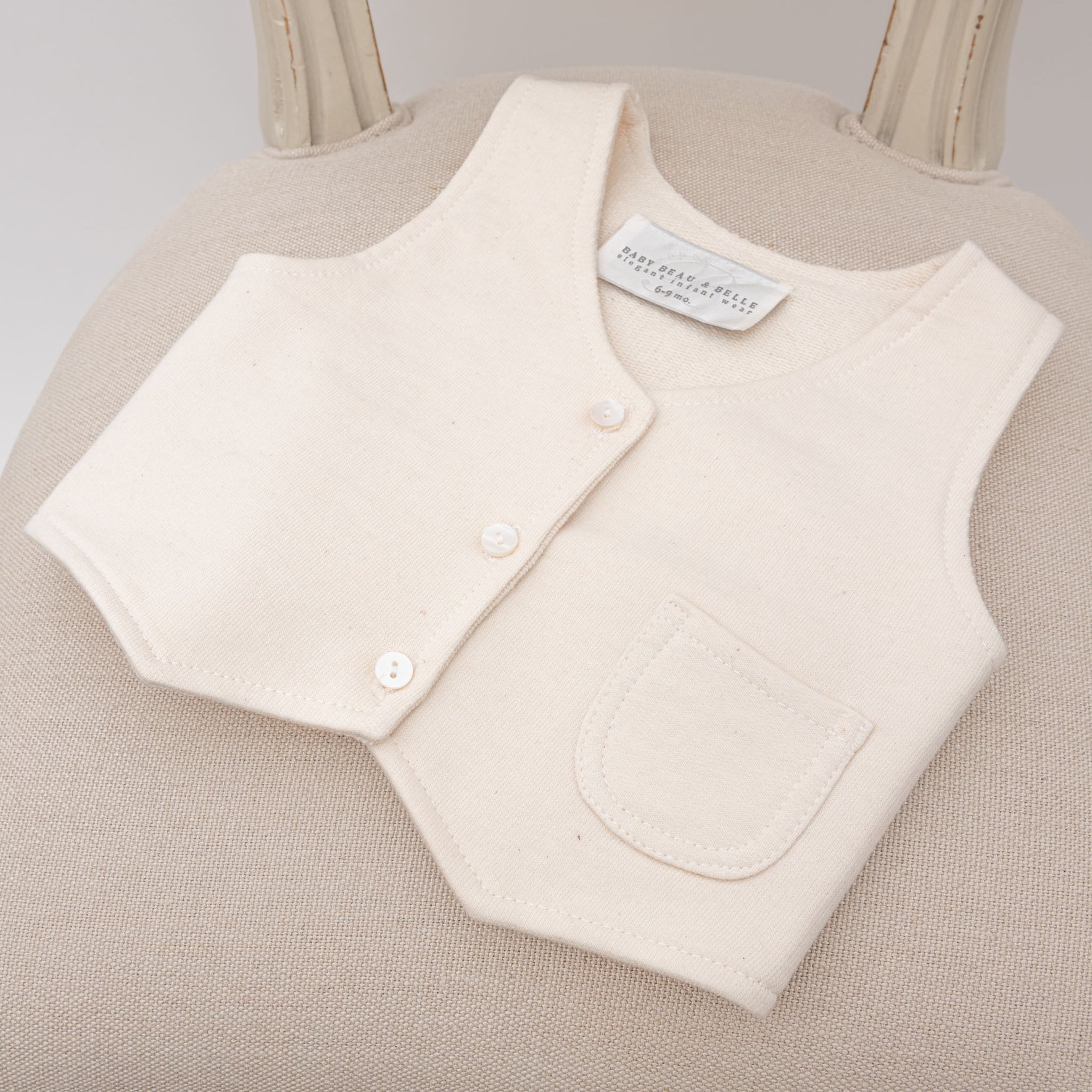 The Milo Tan Vest resting on a cushioned chair, with its clean stitching and classic look visible.