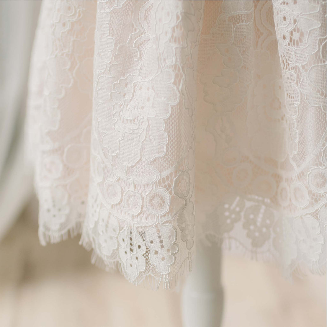 Close-up detail of the Victoria Christening Gown skirt. A detail of the high end baby clothes show the ivory floral lace.
