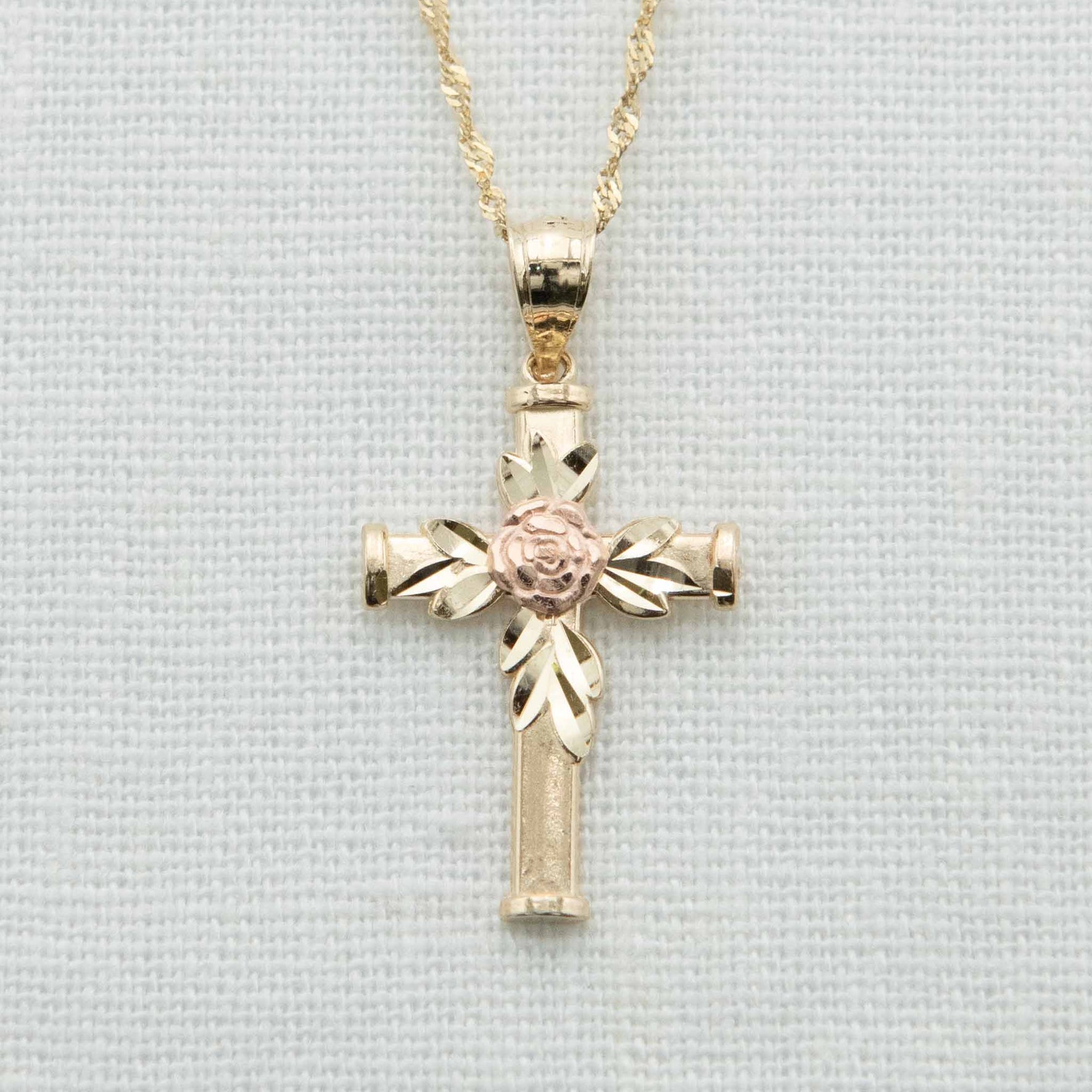 Solid gold cross with gold leaves and rose gold rose detail on chain
