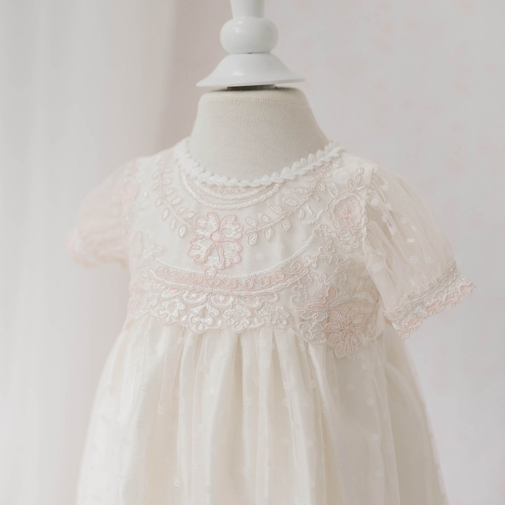 Close-up front view of the Elizabeth Newborn Christening Dress on a mannequin featuring the floral embroidery lace against a white background. Part of the Baby Beau & Belle Baby Girl Christening Dress Collection.
