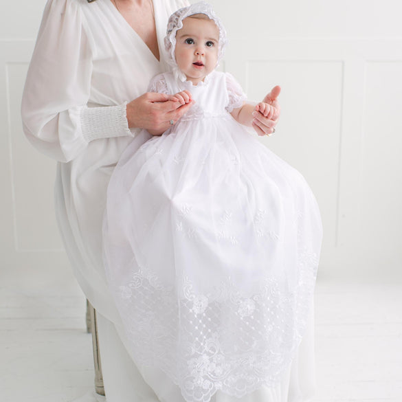 Baby in the Ellie lace gown with a bonnet, sitting on a woman's lap