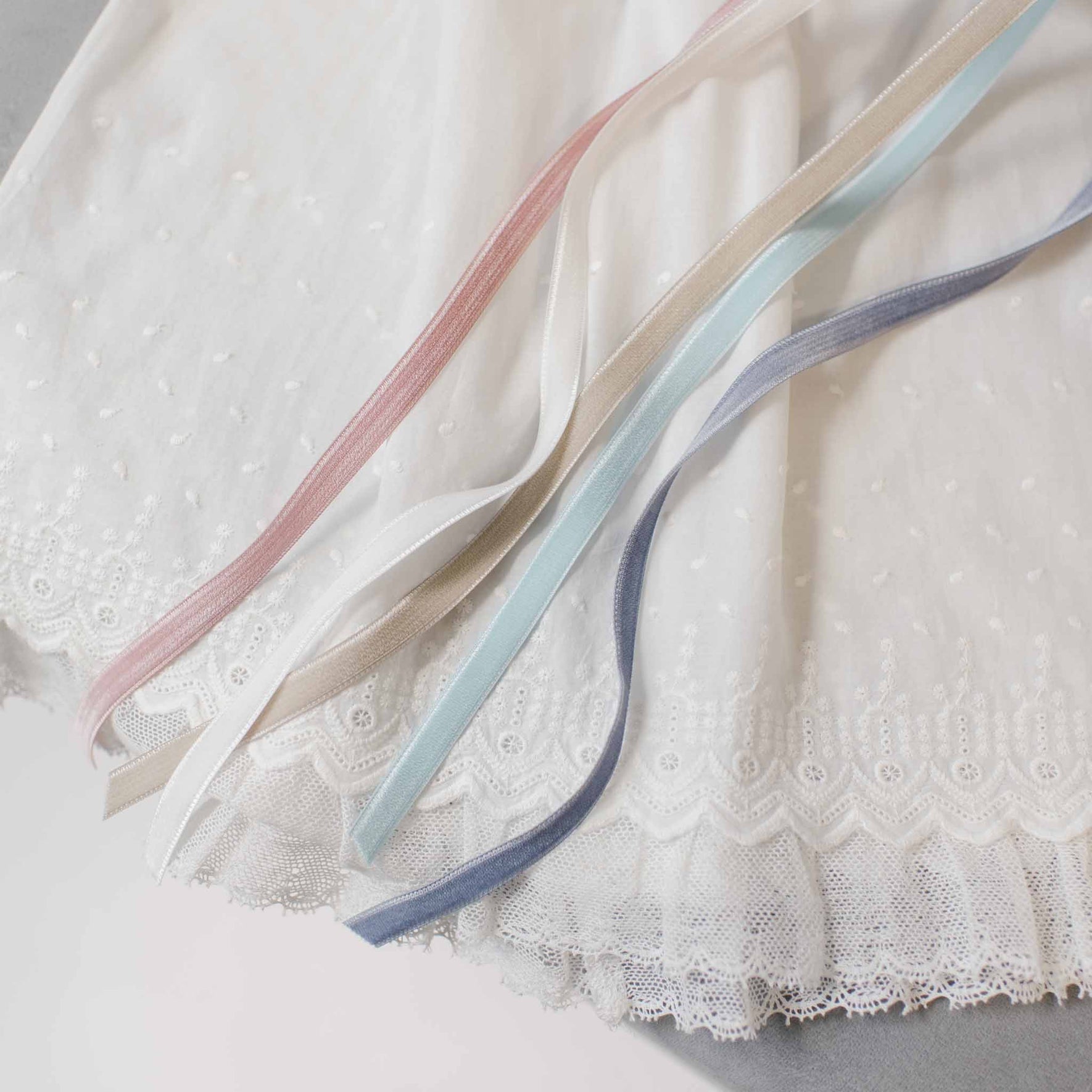 A detailed shot of the Emily Dress & Bloomers fabric, displaying an array of velvet ribbon color options including pink, beige, blue, and gray.