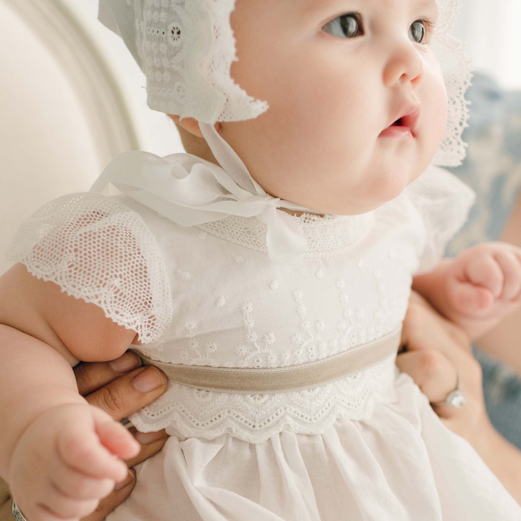 Close-up of the bodice of the Emily Dress, showcasing intricate lace and floral embroidery, with a beige ribbon sash.