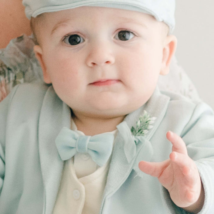 Baby boy wearing the Ezra Powder Blue 4-Piece Suit. Featured in the photo is the Blue Velvet Bow Tie and Boutonniere