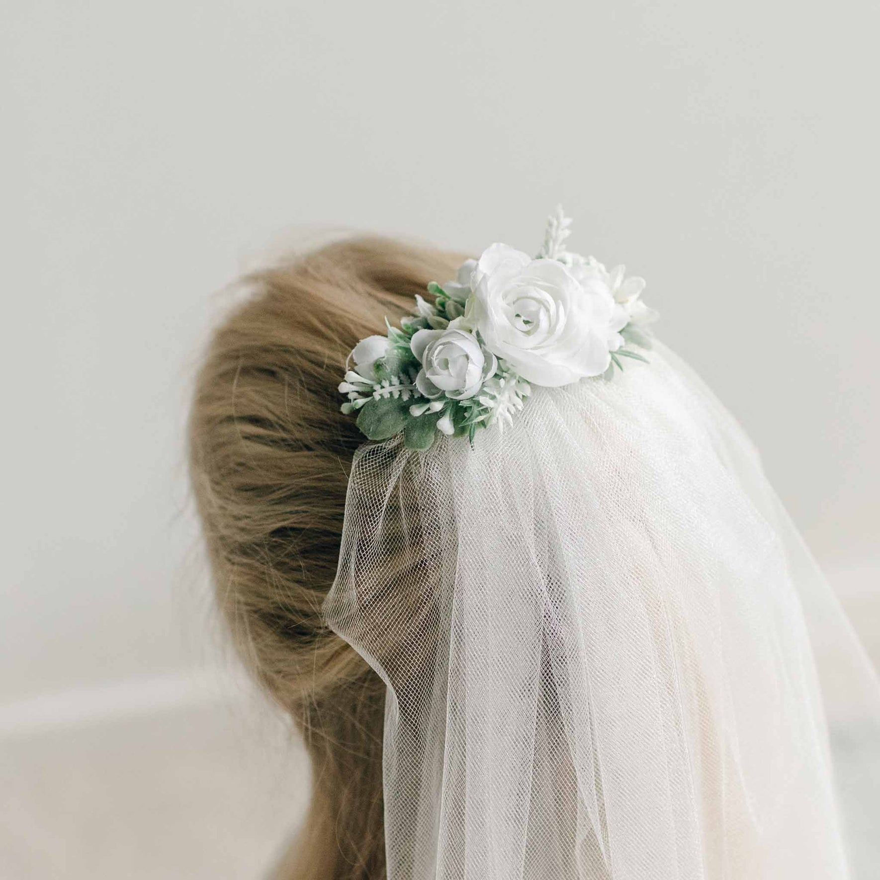 Close-up of the floral headpiece on the First Communion Veil, featuring white roses and greenery.