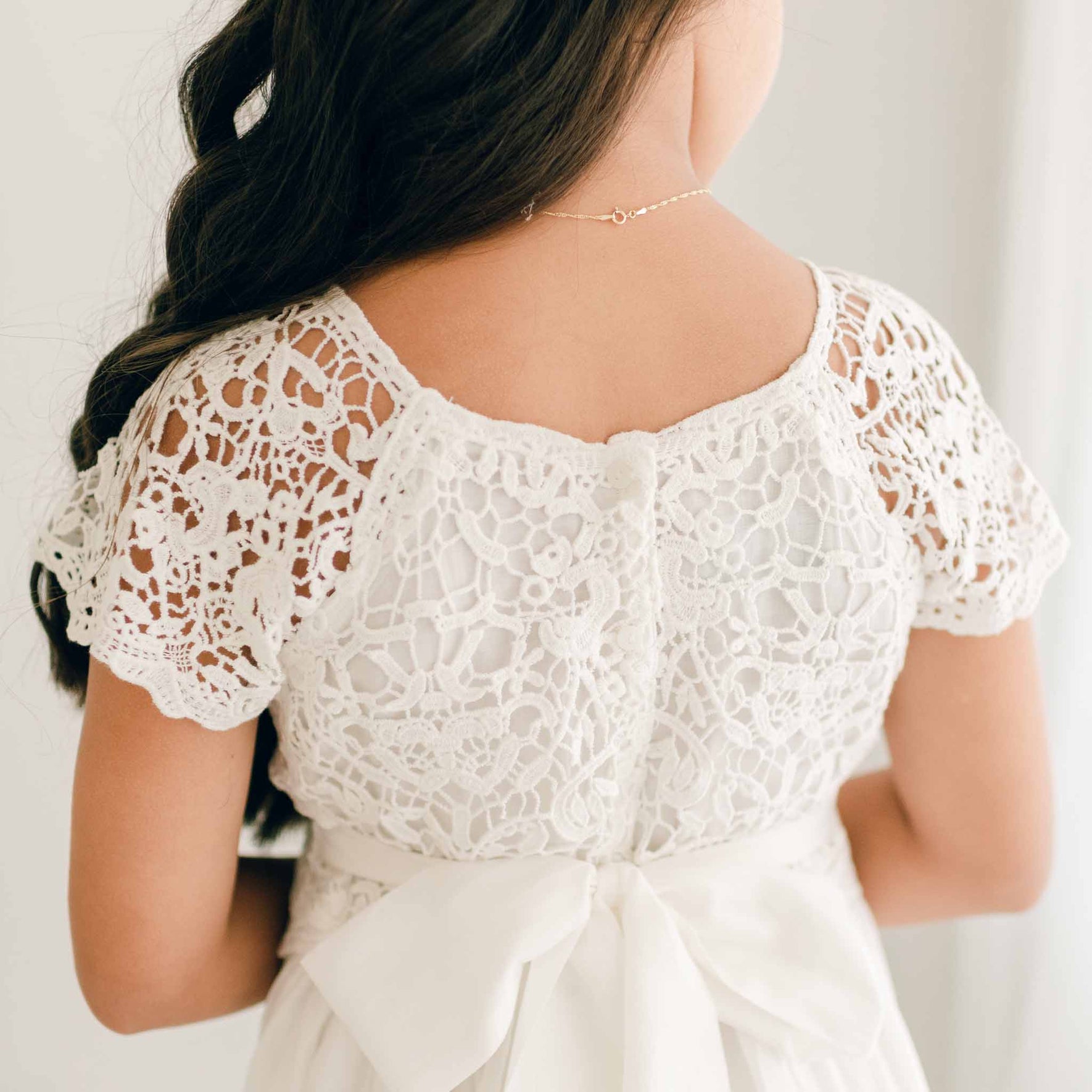 A close-up of the Grace Girls Lace Dress back detailing, highlighting the intricate lace design and soft ivory buttons.