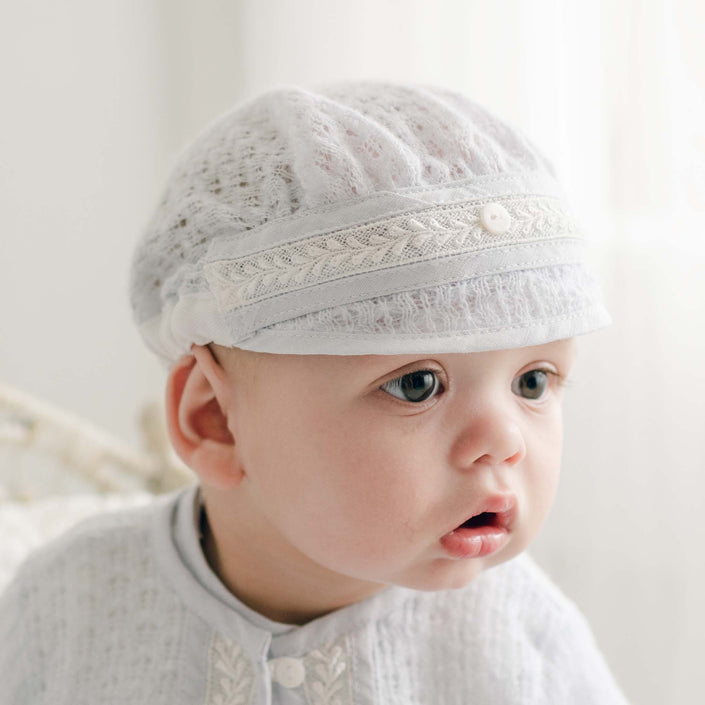 Detailed view of the Harrison Blue Knit Christening Hat with elegant lace and pearl button accent.