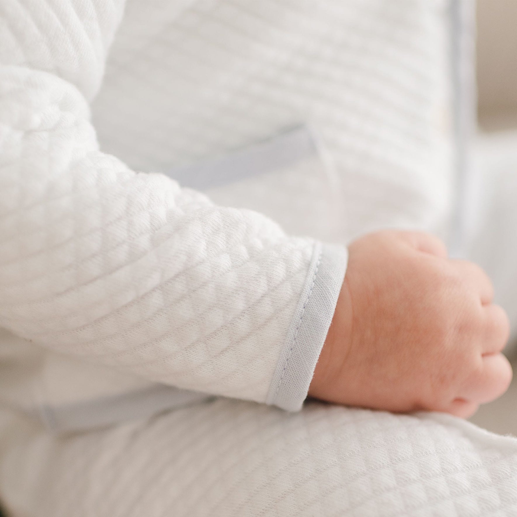 Detailed view of the Harrison Christening Pants Suit sleeve, showcasing the textured quilted fabric and pale blue trim along the cuff.