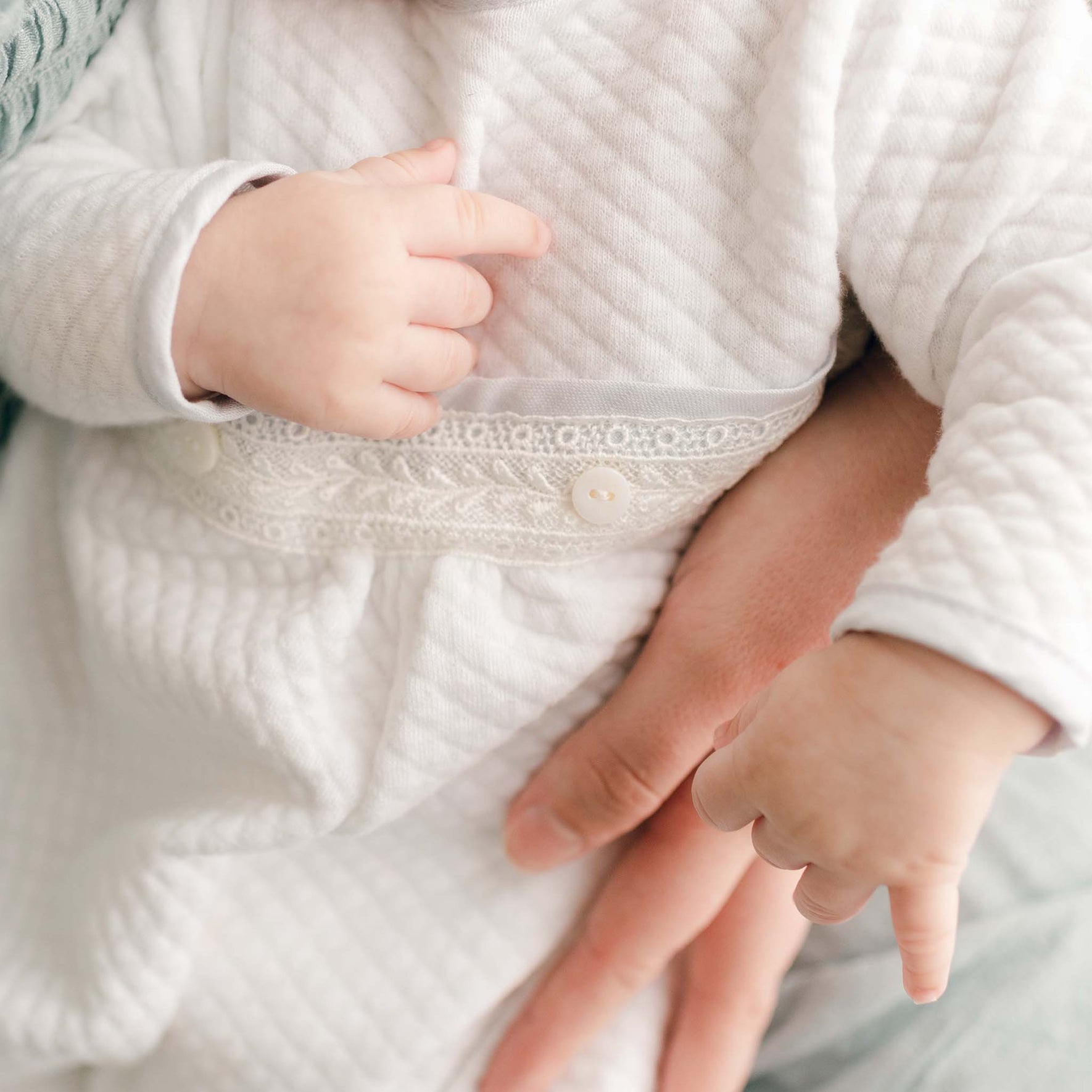 Detailed view of the delicate lace and buttons on the Harrison Newborn Romper, emphasizing its elegant design for a christening.