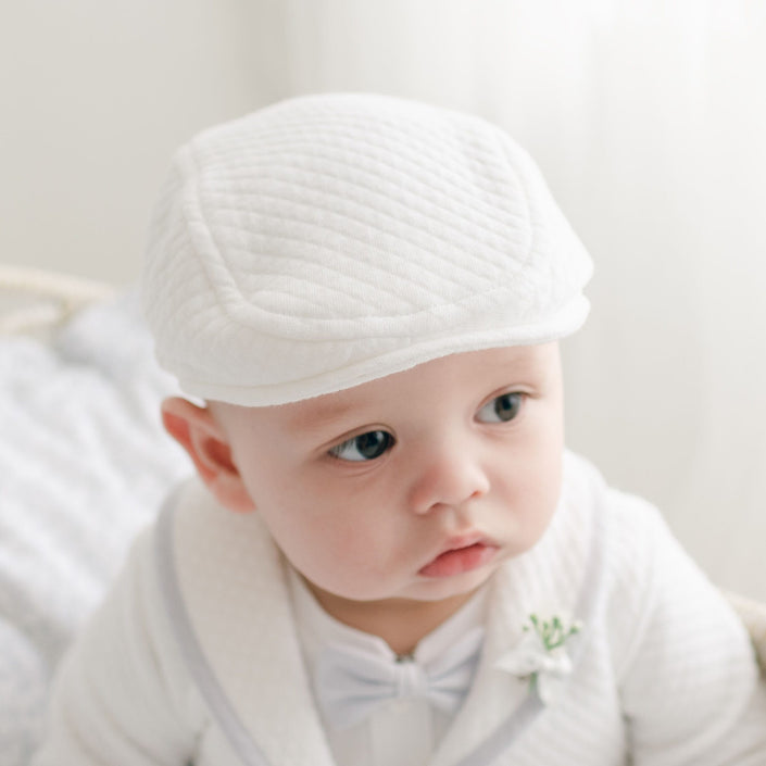Close-up of an infant wearing the Harrison Newsboy Cap, crafted from white quilted fabric with a classic and refined style.