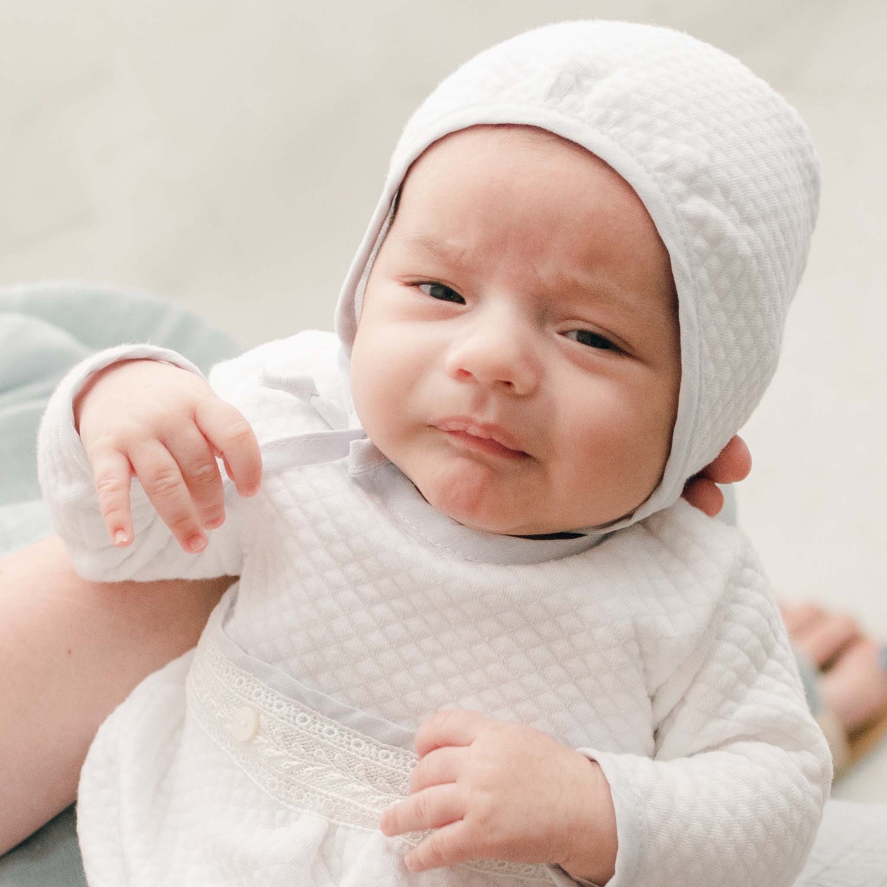 Harrison Quilted Bonnet shown on a baby, with a focus on its classic quilted fabric and thoughtful details.