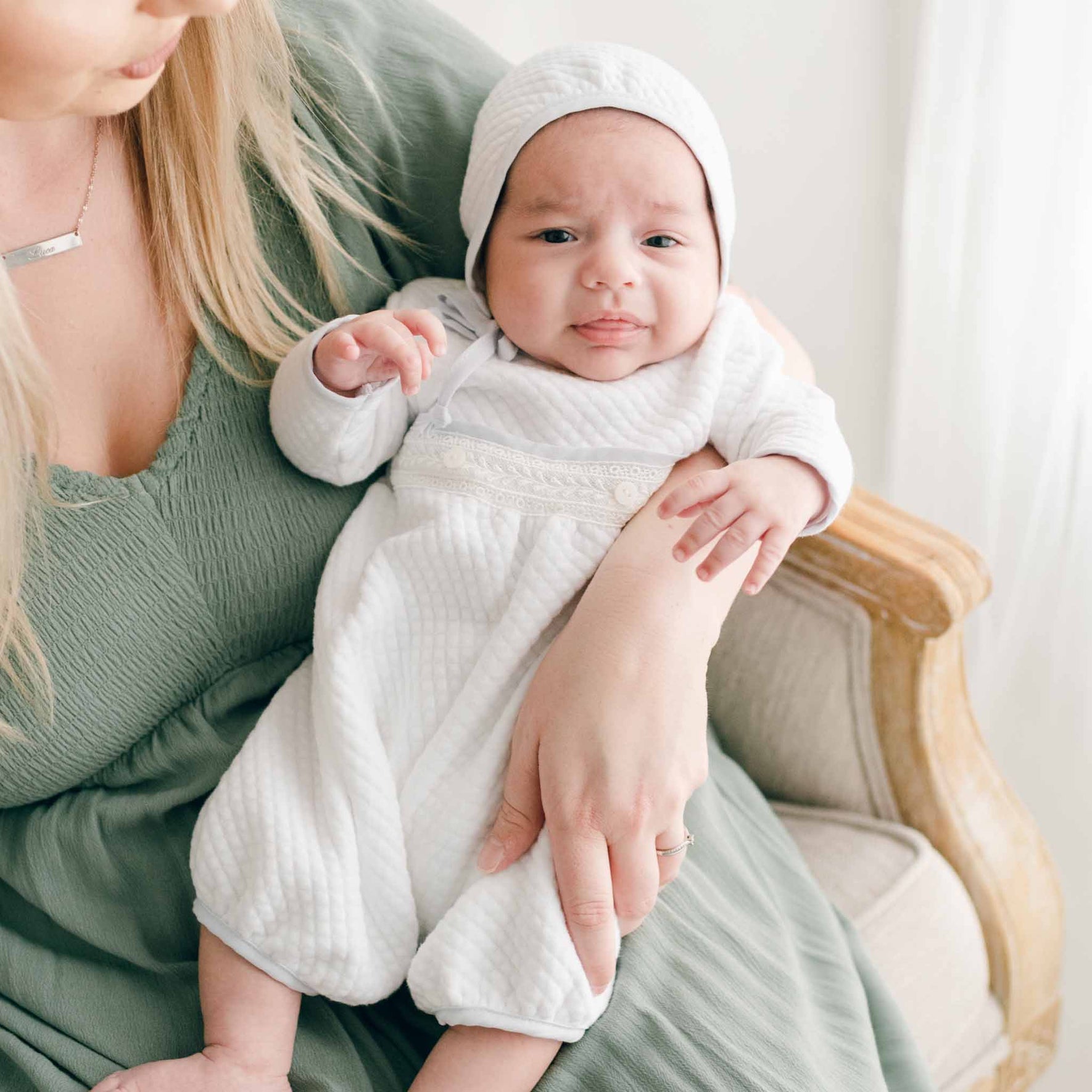 Baby in the Harrison Quilted Bonnet resting in a caregiver’s arms, capturing the cozy and tailored fit.