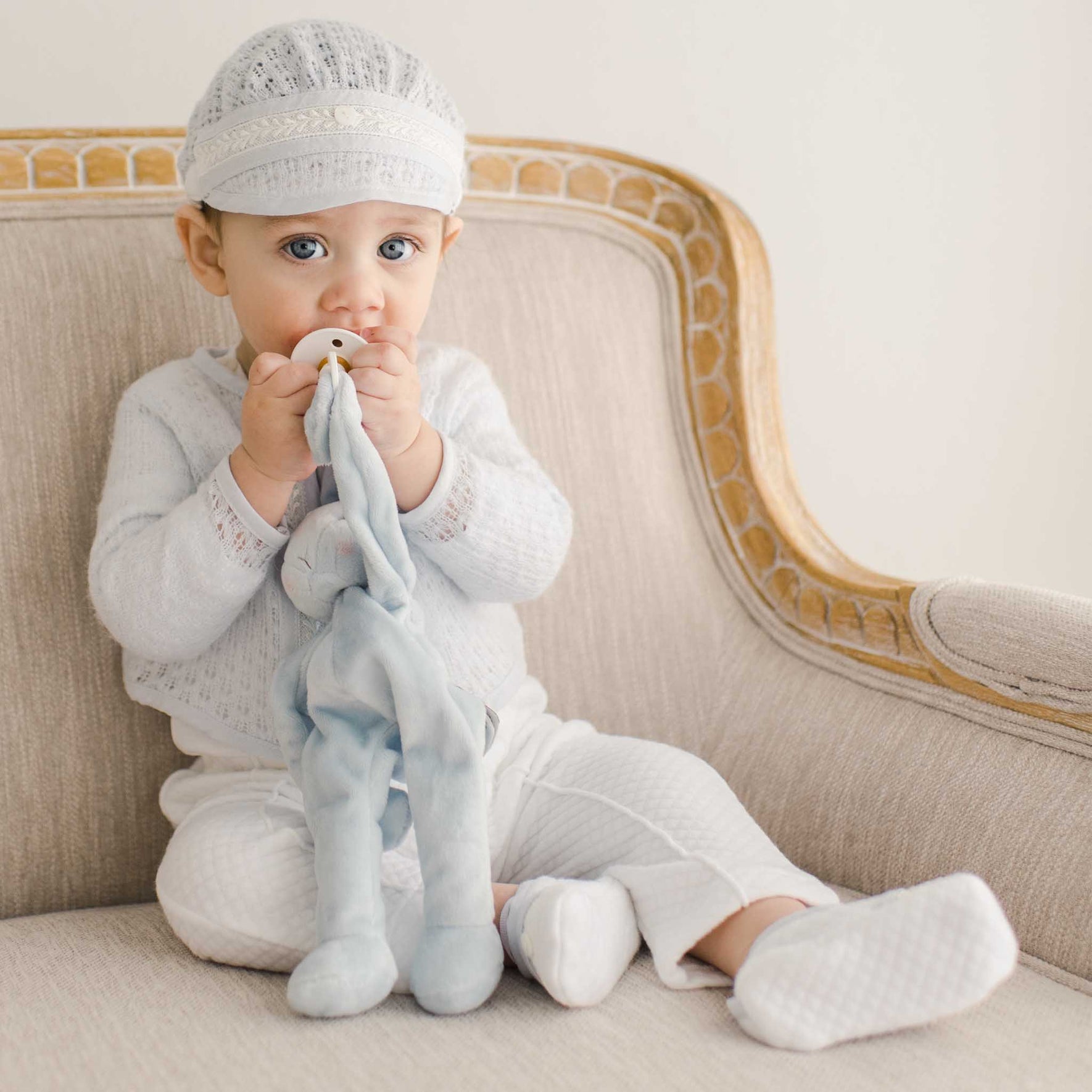 Baby seated with a plush toy, dressed in the Harrison Sweater 3-Piece Pants Suit, featuring intricate lacework on the sweater.