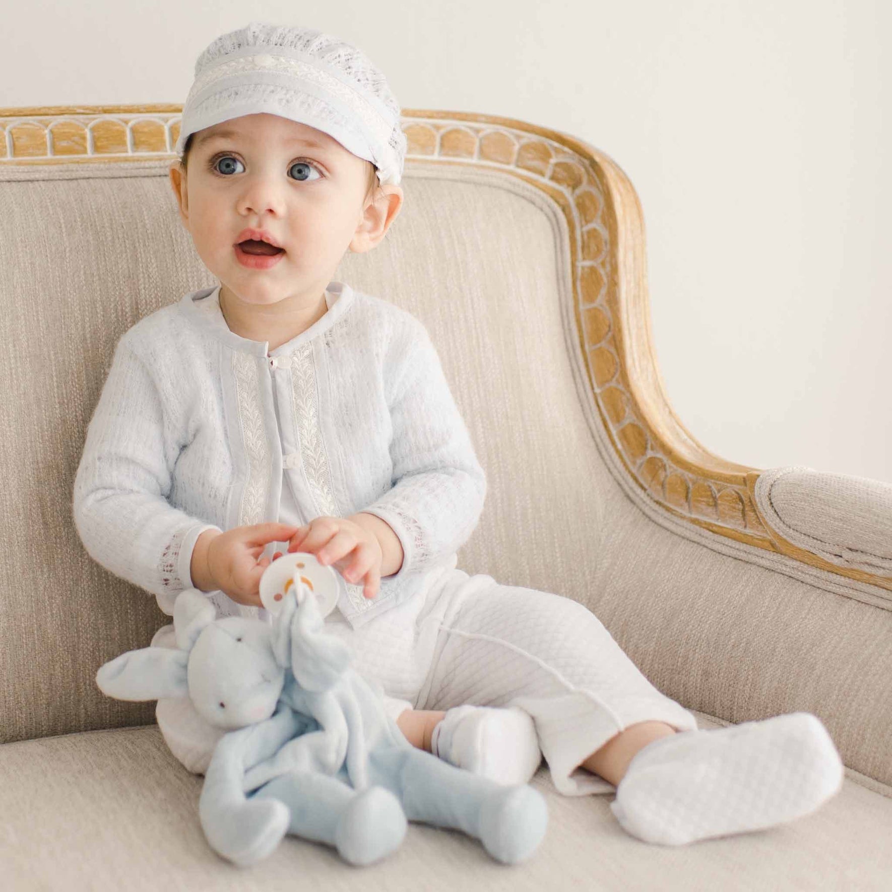 Baby in the Harrison Sweater 3-Piece Pants Suit, holding a plush toy, with a cozy lace-knit sweater and textured pants.
