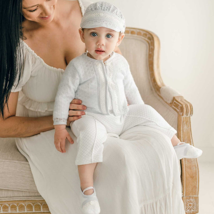 Baby wearing the Harrison Sweater 3-Piece Pants Suit, seated on an armchair, featuring a textured sweater with lace detailing.