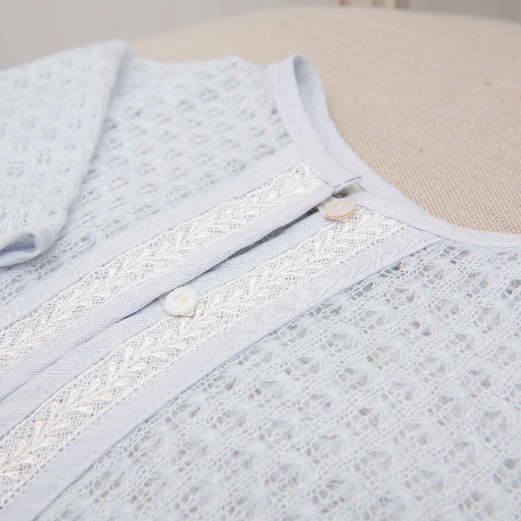 Close-up of the lace-trimmed blue sweater, highlighting the intricate embroidery and button detailing.