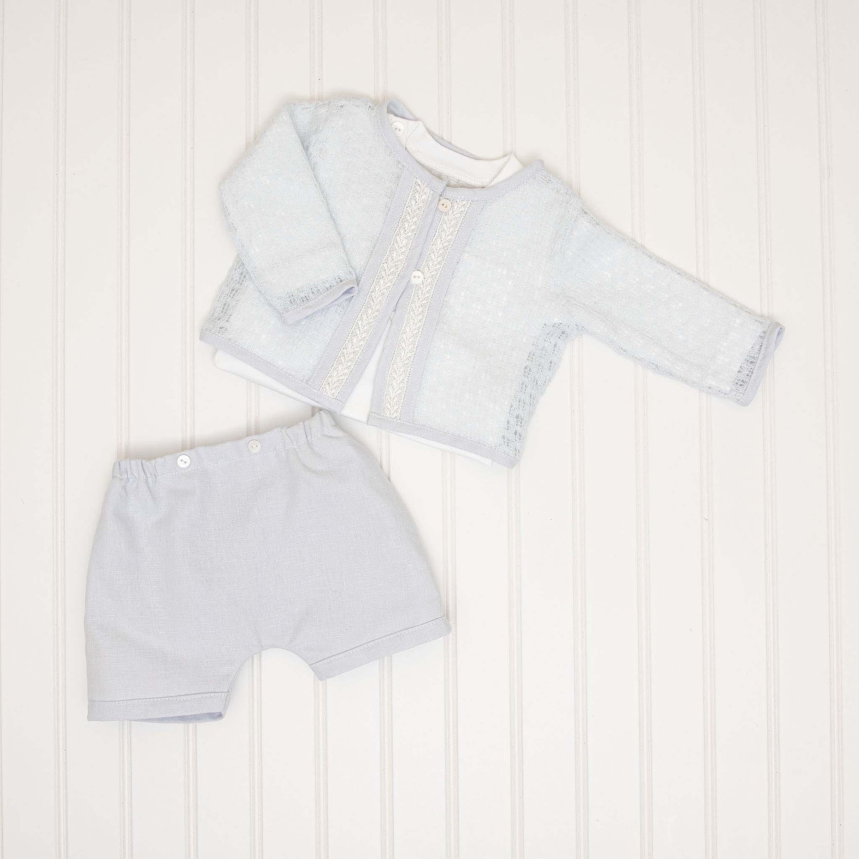 A detailed flat lay of the threeHarrison Sweater 3-Piece Shorts Suit, including a light blue lace-trimmed sweater, matching shorts, and an undershirt.