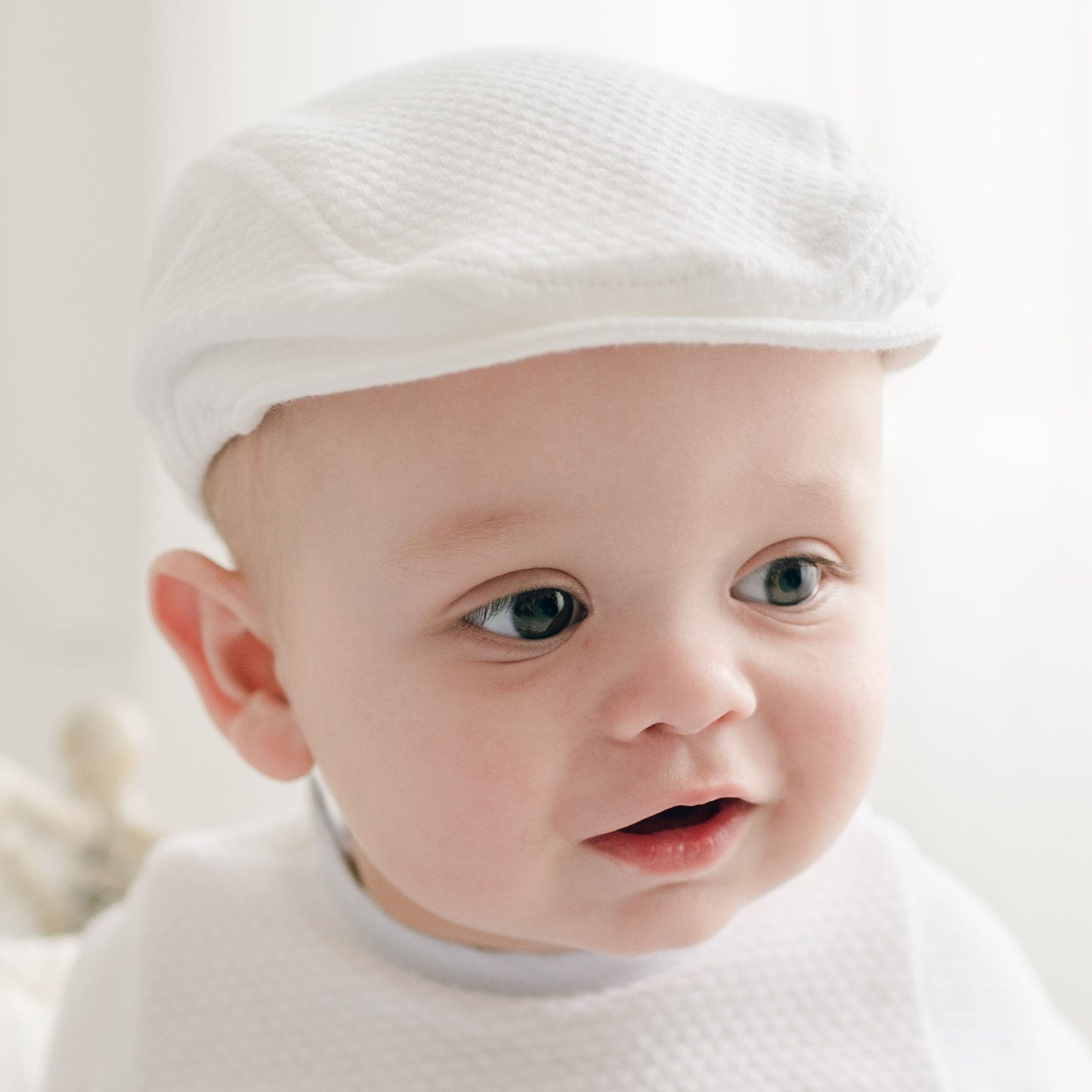 Side profile of a baby in the Harrison Textured Christening Newsboy Cap, highlighting the refined details and comfortable fit.