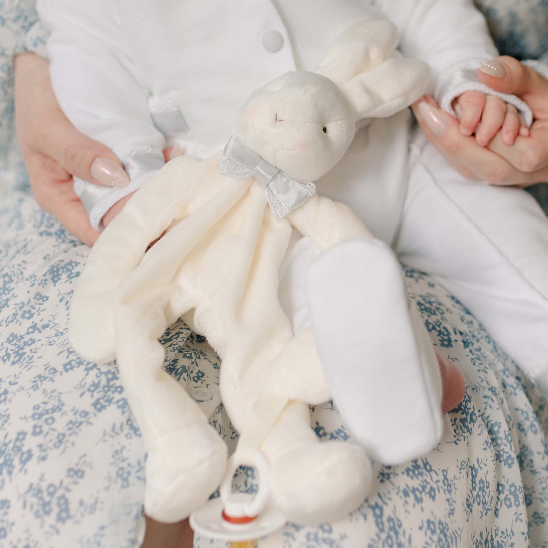 Close up photo of the Henry Silly Bunny Buddy held by a baby sitting on his mother's lap. Details show the lace and blue silk ribbon bow tie. Perfect as unique baby gifts.
