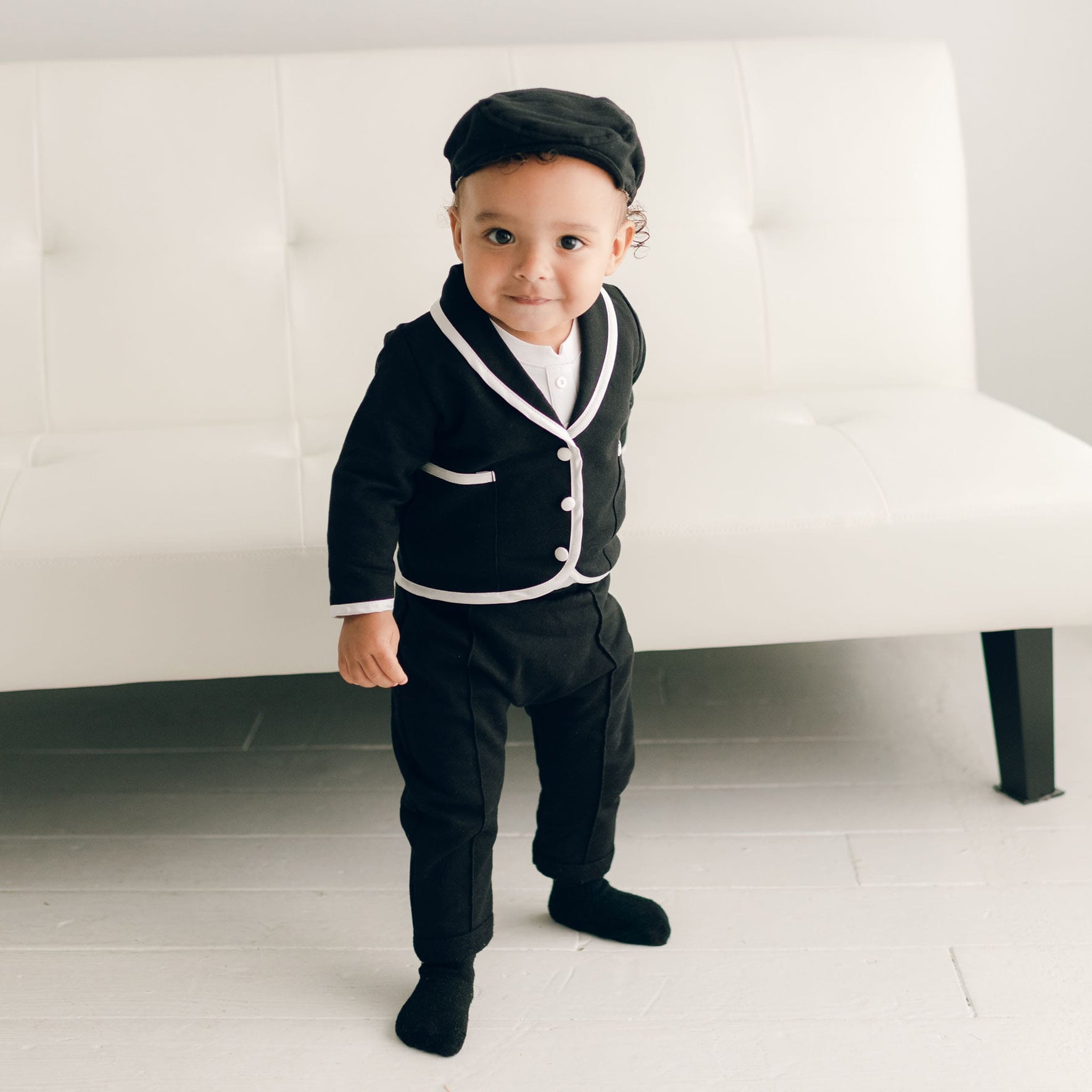 A toddler confidently standing in the black James 3-Piece Suit, showing the full suit with white trim details.