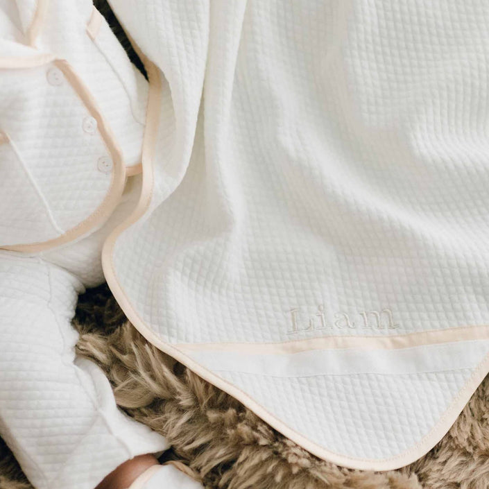 Photo of a baby sitting on a brown fur blanket. The baby is wearing the Liam 3-Piece Suit and is covered with the Liam Personalized Blanket