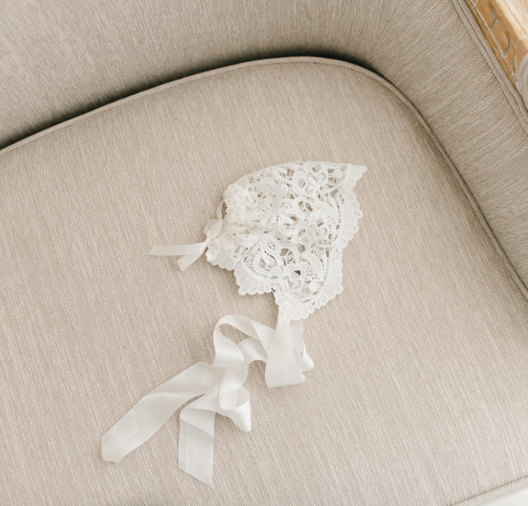 Flat lay of the Lola Lace Christening Bonnet, featuring intricate ivory lace with floral edge detailing.