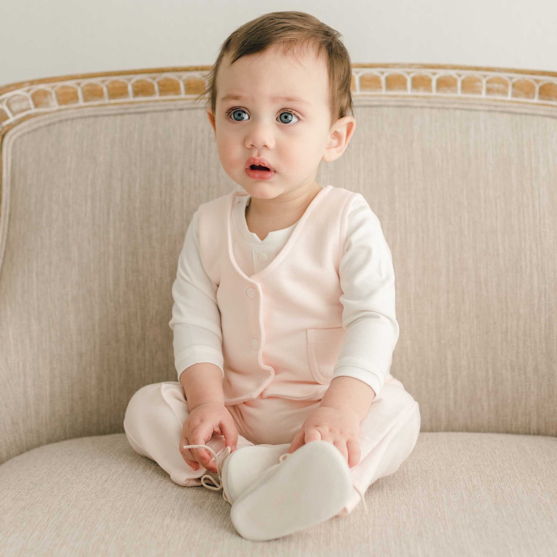 A baby sitting in the Milo Blush Vest and matching outfit.