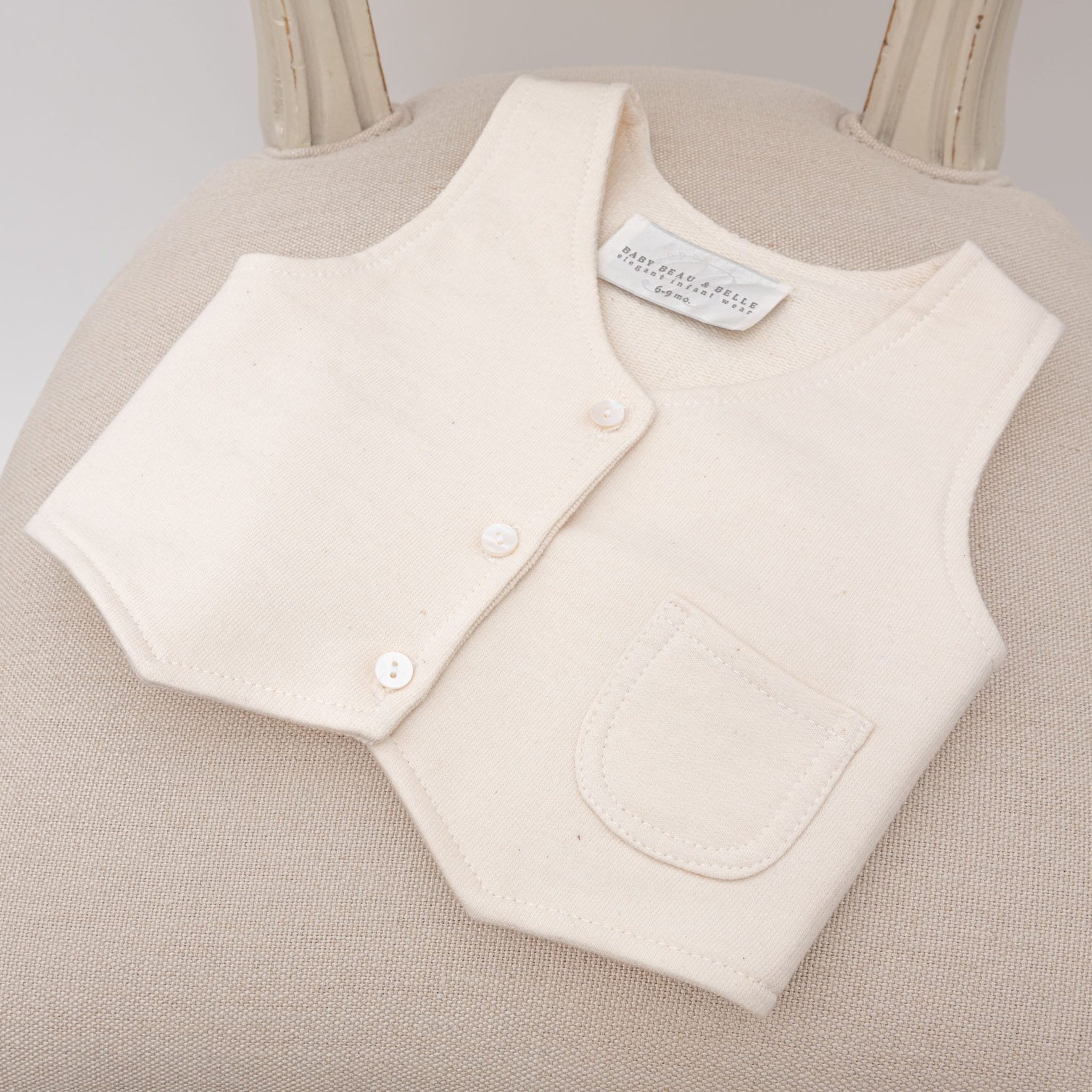 The Milo Tan Vest resting on a cushioned chair, with its clean stitching and classic look visible.