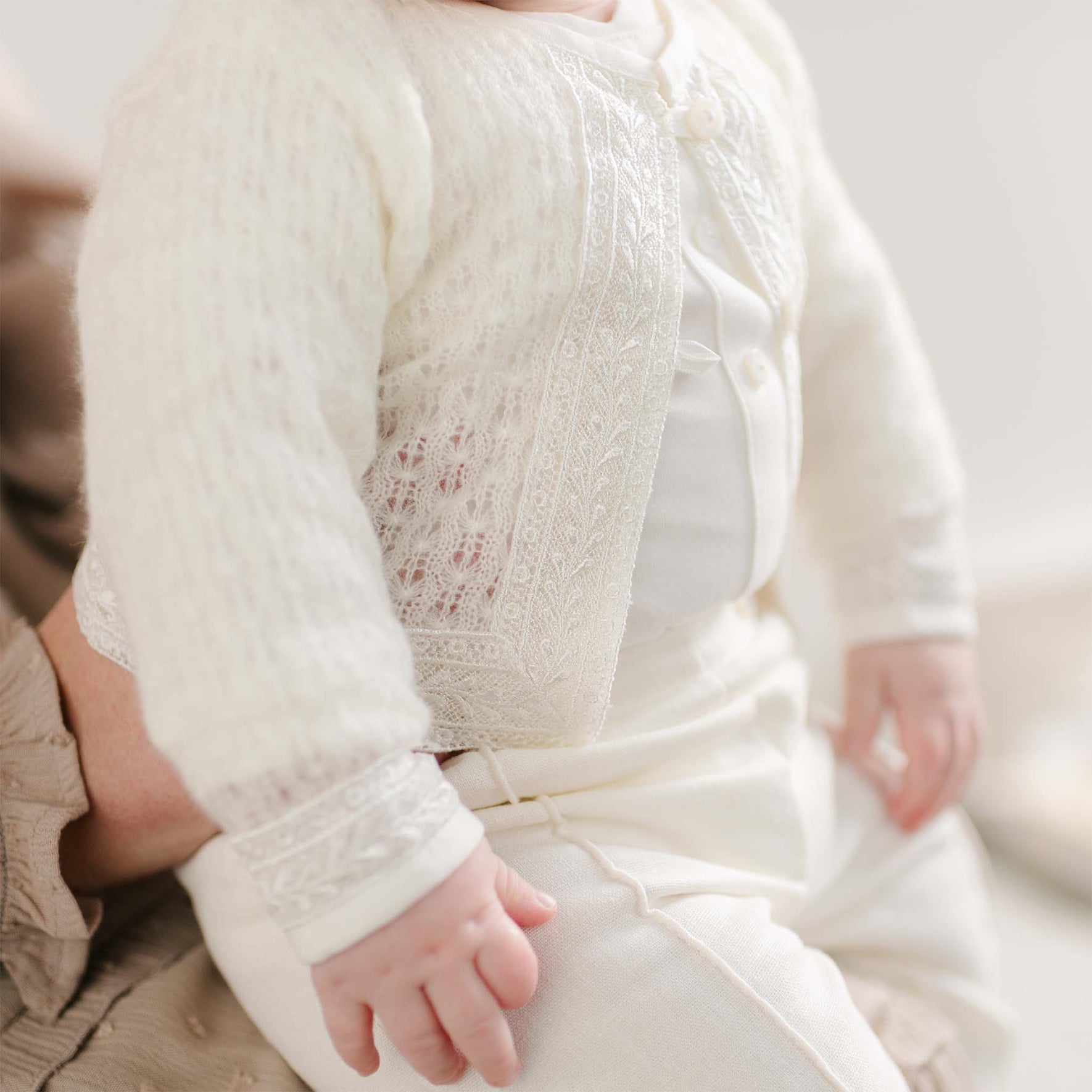 A close-up of the Oliver Sweater’s lace-trimmed front panel and delicate pearl buttons.