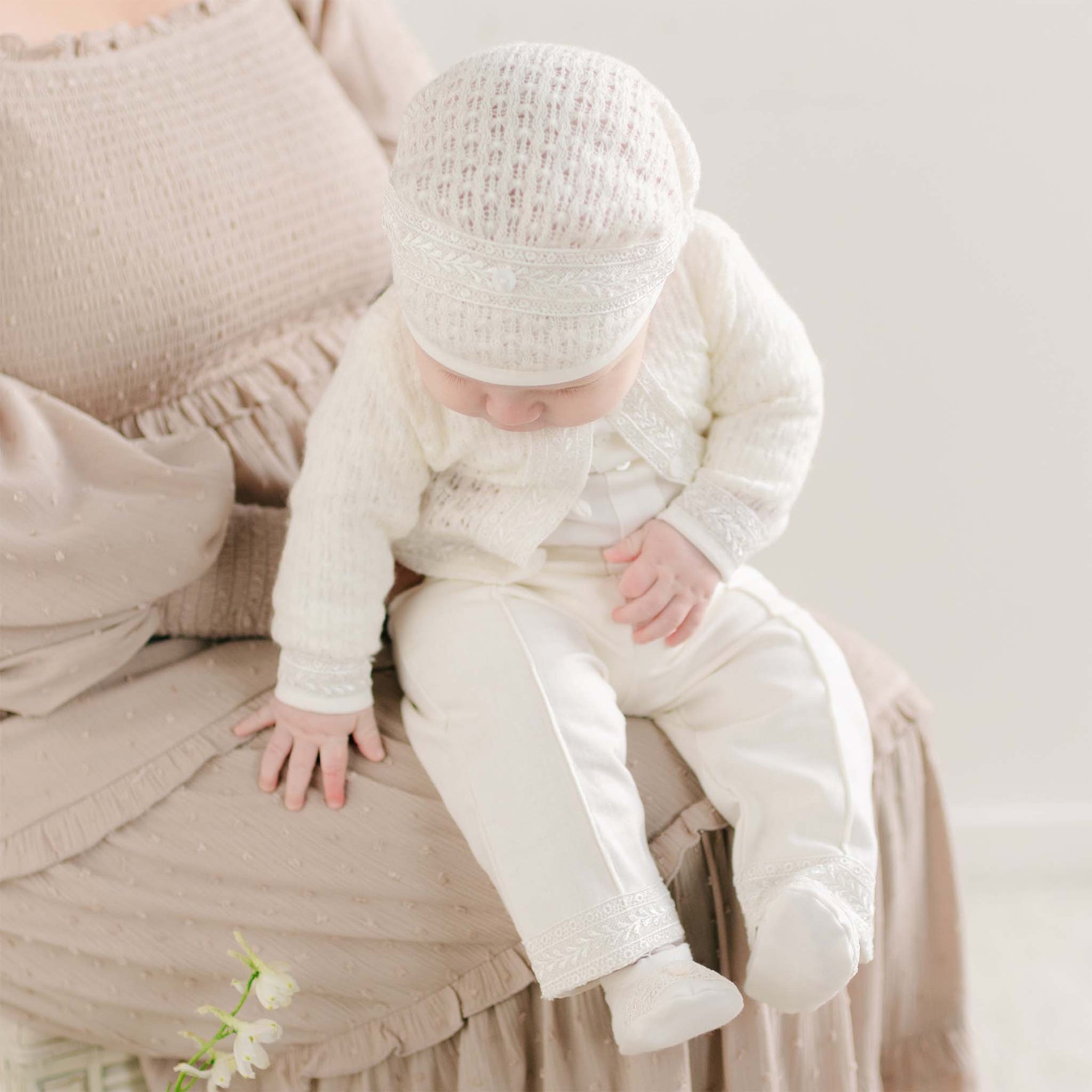 A baby looking down in the Oliver Sweater Pants Suit, showing the soft knit fabric and lace accents.