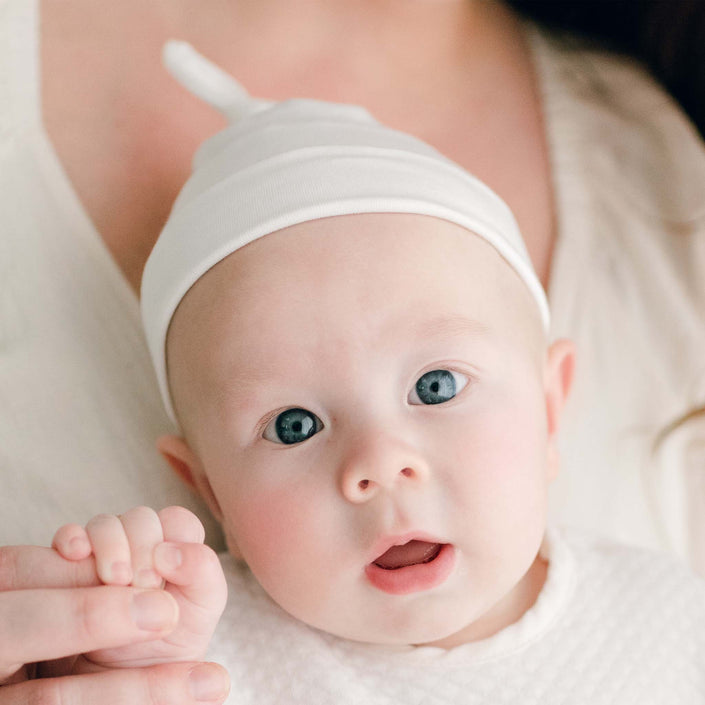Newborn baby wearing the Owen Knot Cap made from an ivory soft pima cotton with a knot design