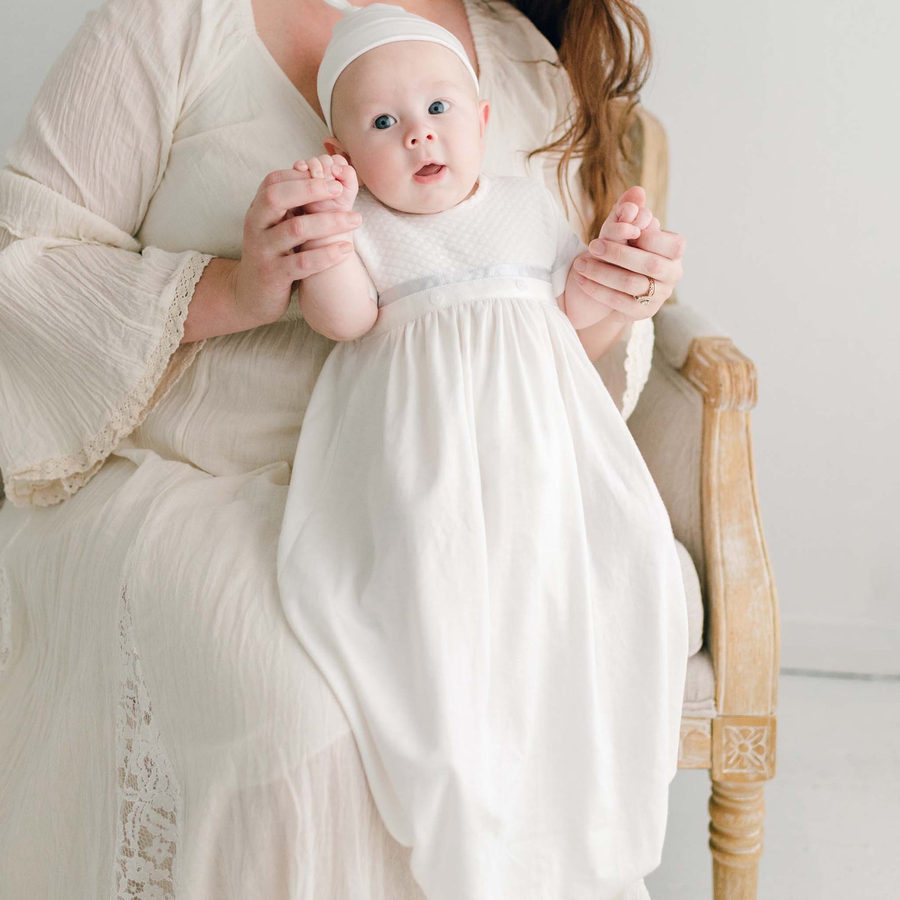 Baby boy sitting on his mother's lap. He is wearing the Owen Layette and Knot Cap