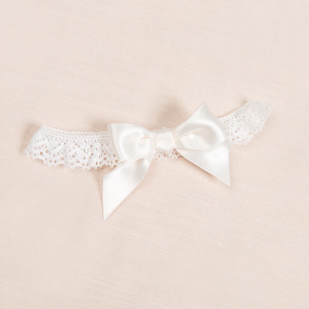 Flat lay photo of Penelope lace headband with bow.