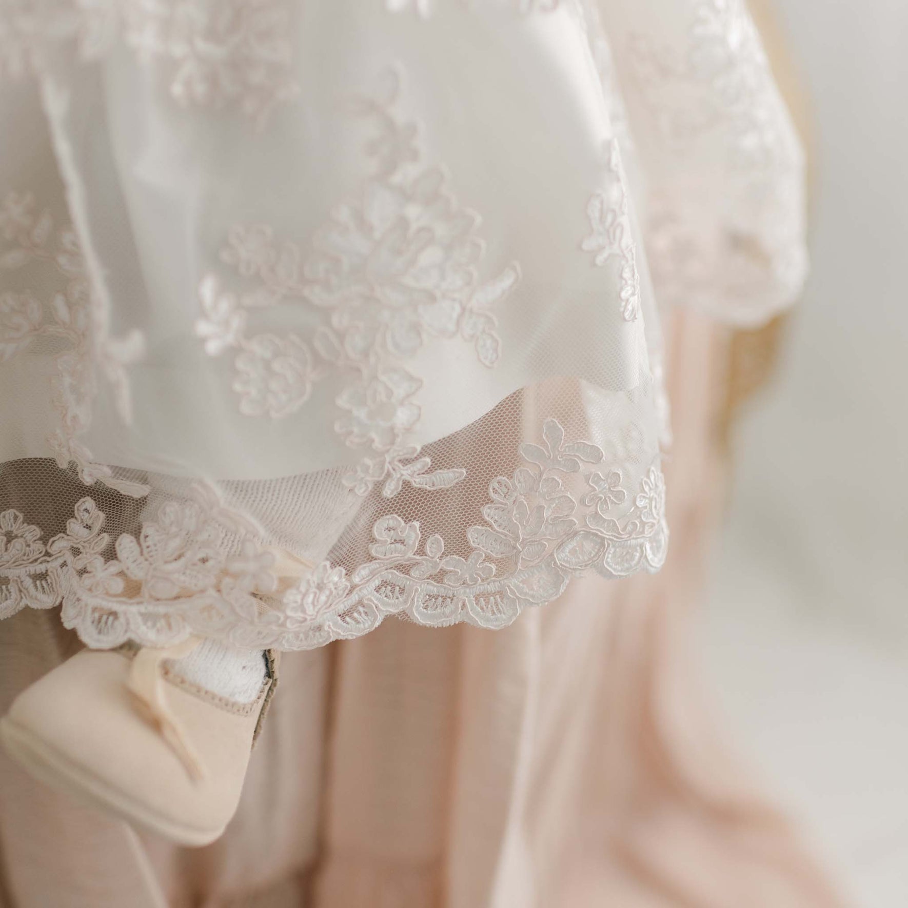 Baptism dress hem embroidered lace detail, fancy baby dress on baby girl wearing tights and suede Mary Jane shoes