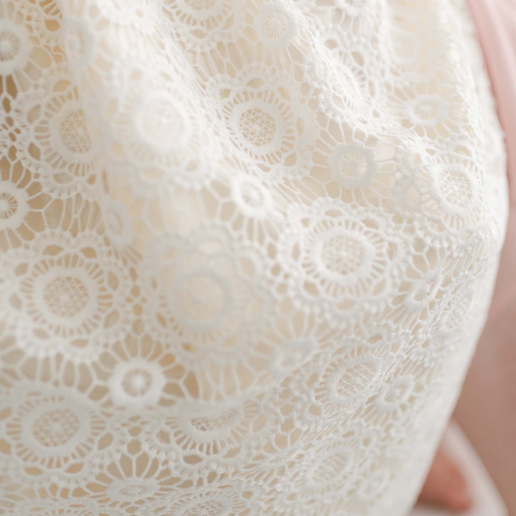 Detailed close-up of the floral lace pattern on the Poppy Christening Gown, highlighting the intricate craftsmanship and elegant texture.