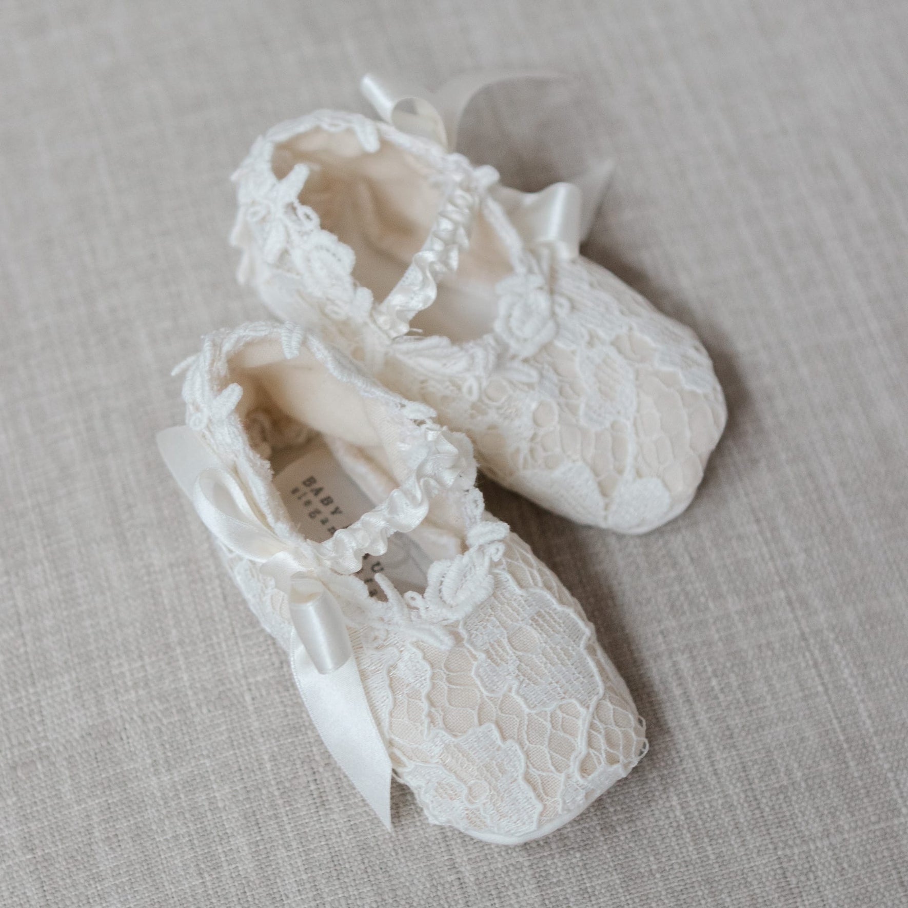 Pair of lace baby shoes on a textured surface