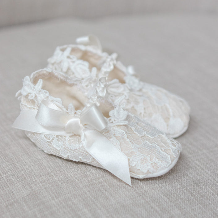 Lace baby shoes with a bow on a light gray background