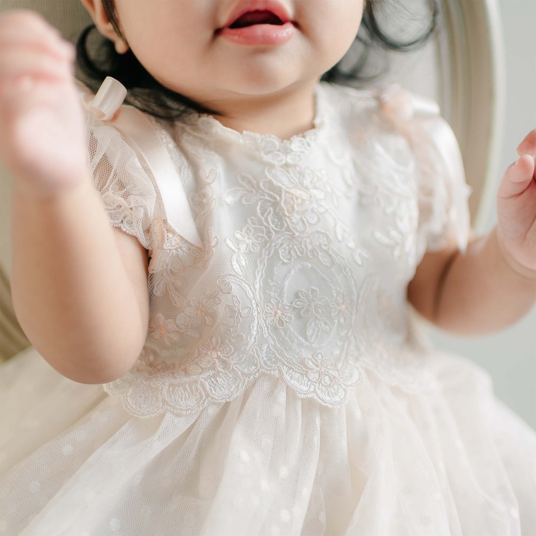 A close-up of the bodice of the Sophia Dress, showing intricate embroidery and delicate satin ribbon bows.