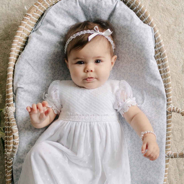Baby wearing the Stella Silk Ribbon Headband and matching Dress against a patterned blanket. 