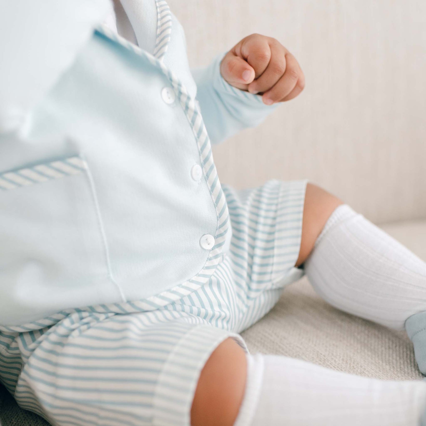 Close detail of a boy wearing the blue Theodore Short Suit, including the jacket, shorts, and onesie (and matching Theodore Newsboy Cap).