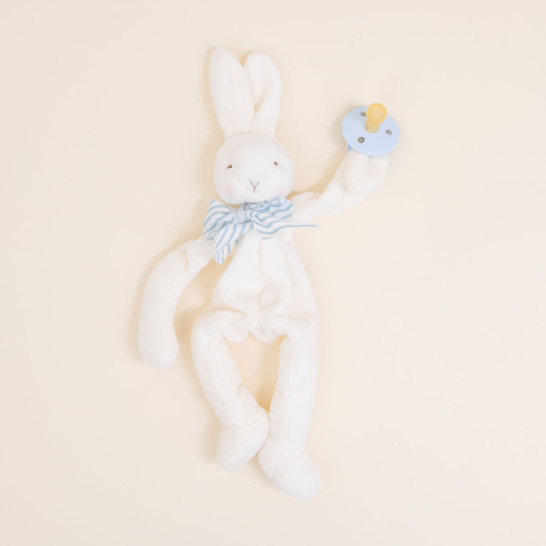 Flat lay photo of the blue Theodore Bunny Buddy Pacifier Holder. Stuffed animal floppy bunny made from a soft velour.
